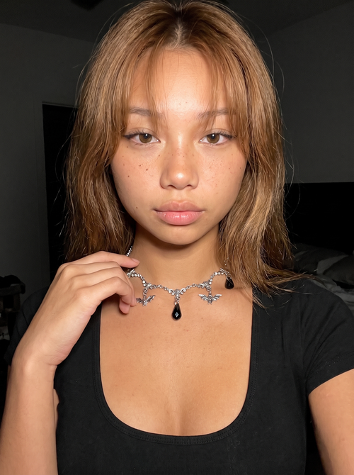 Silver bat charm choker with black teardrop stone worn at the throat